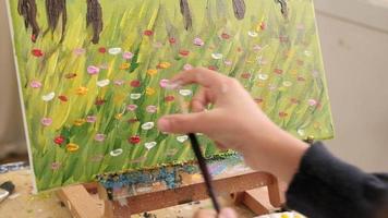 avvicinamento sparo, acrilico colore pittura tecnica, spruzzatura pennello di mano su tela, alunno ragazza nel un arte aula, elementare scuola studio formazione scolastica con creativo, selettivo messa a fuoco su immagine. video