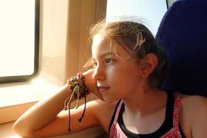 la niña está sentada cerca de la ventana del ferry foto