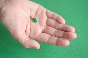 Take the medicine. Mature woman hand holds a capsule. Colorful pills. Treatment concept. Grandmothers hand. Capsule with granules. photo