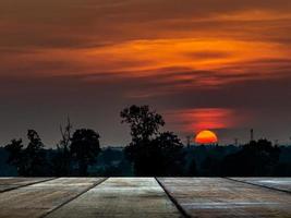 An old wooden table against the backdrop of the shadow of the forest with sunset at dusk. photo