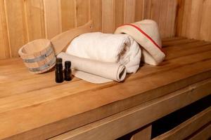 Traditional old Russian bathhouse SPA Concept. Interior details Finnish sauna steam room with traditional sauna accessories set basin towel aroma oil scoop felt. Relax country village bath concept. photo