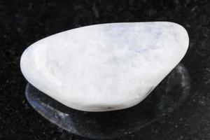 pebble of white moonstone adularia gem on dark photo