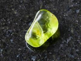 tumbled Peridot gem stone on dark background photo