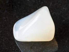 tumbled white Agate gemstone on dark background photo