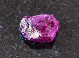 unpolished Rhodolite pyrope crystal on black photo