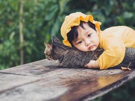 Asian baby of Thai nationality and cat at De mala Cafe, Thung Saliam, Sukhothai, Thailand. photo