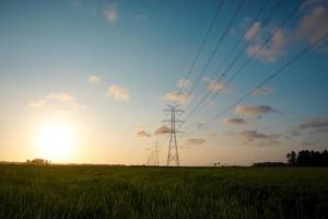 cielo crepuscular por la tarde en un prado o campo de arroz en el fondo hay una torre eléctrica que conecta de ciudad en ciudad foto