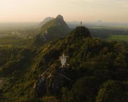 una vista aérea de cristo redentor y buda en la montaña se destaca prominentemente en hup pha sawan en ratchaburi cerca de bangkok, tailandia foto