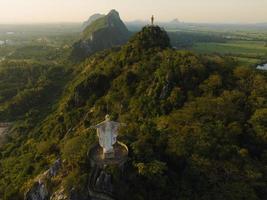 una vista aérea de cristo redentor y buda en la montaña se destaca prominentemente en hup pha sawan en ratchaburi cerca de bangkok, tailandia foto