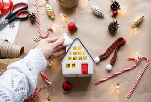 Cozy house in Christmas decor layout, warm knitted scarf, hat, winterization. Winter, snow - home insulation, protection from cold weather, room heating system. Festive mood, Christmas, New Year photo