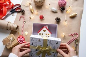 Key to house with keychain on cozy home in gift box with Christmas decor packaging. Pack present for New Year, Christmas. Building, project, moving to new house, mortgage, rent, purchase real estate photo