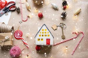 Key to the house with a keychain on a cozy home with a Christmas decor layout. A gift for New Year, Christmas. Building, design, project, moving to new house, mortgage, rent and purchase real estate photo