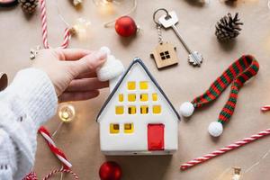 Key to the house with a keychain on a cozy home with a Christmas decor layout. A gift for New Year, Christmas. Building, design, project, moving to new house, mortgage, rent and purchase real estate photo