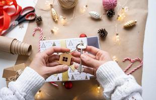 Key to house with keychain on cozy home in gift box with Christmas decor packaging. Pack present for New Year, Christmas. Building, project, moving to new house, mortgage, rent, purchase real estate photo