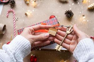 Key to house with keychain on cozy home in gift box with Christmas decor packaging. Pack present for New Year, Christmas. Building, project, moving to new house, mortgage, rent, purchase real estate photo