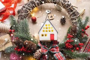 Key to the house with a keychain on a cozy home with a Christmas decor layout. A gift for New Year, Christmas. Building, design, project, moving to new house, mortgage, rent and purchase real estate photo