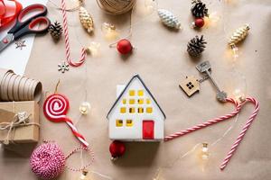 Key to the house with a keychain on a cozy home with a Christmas decor layout. A gift for New Year, Christmas. Building, design, project, moving to new house, mortgage, rent and purchase real estate photo