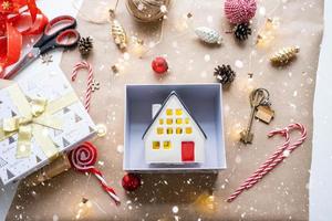 Key to house with keychain on cozy home in gift box with Christmas decor packaging. Pack present for New Year, Christmas. Building, project, moving to new house, mortgage, rent, purchase real estate photo