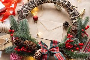 empaque un regalo para navidad y año nuevo en papel kraft, conos, cinta adhesiva, tijeras. etiquetas con maqueta, decoración natural, hechas a mano, bricolaje. Actitud festiva. plano, fondo foto
