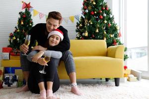 Beautiful young Asian couple is holding glasses of champagne, smiling and affectionate while celebrating New Year at home photo