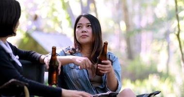 grupo belas mulheres asiáticas amigos viajantes relaxando na frente da barraca de acampamento, eles gostam de conversar e beber cerveja com diversão e feliz juntos video