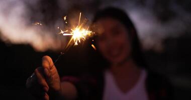 selectief focus een vuurwerk brandend sterretje in vrouw hand- in nieuw jaar festival, ze genieten naar spelen sparkly in haar hand- Aan nieuw jaar partij nacht video