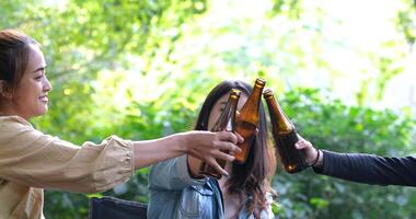 gruppo di belle donne asiatiche amici viaggiatori che si rilassano sulle sedie da campo in tenda, stanno esultando e bevendo birra durante il campeggio, parlando con divertimento e felici insieme video