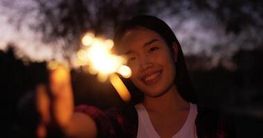 selektiv fokus en fyrverkeri brinnande sparkler i kvinna hand i ny år festival, hon njut av vinka hand till spelar glittrande i hand på ny år fest natt video