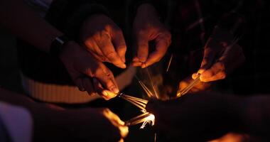 selettivo messa a fuoco, vicino su gruppo di mani Tenere fuoco ardente sparklers nel nuovo anno festa video