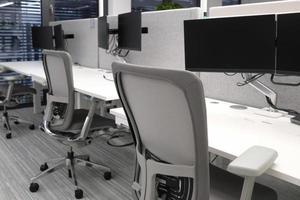 Empty desks in an office building with several monitors photo