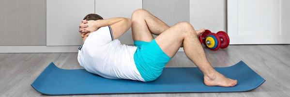 A strong, healthy man with muscles, training at home in the plank position. Fitness at home. Banner photo