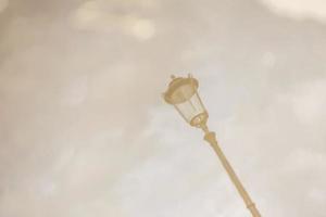 Street lamp. Reflection in a puddle against a cloudy sky in cloudy weather. Blurry image photo