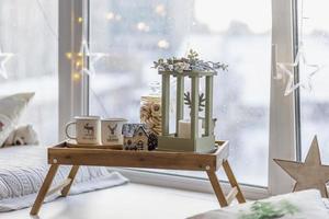 Morning Christmas coffee with marshmallows and Christmas decorations on a tray table by the window on the windowsill photo