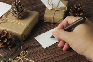 male hands wrapping new year gifts and writing cards On a brown wooden table. photo