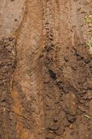 Selective focus of muddy road with marks from motorcycle wheels photo