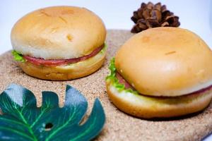 Selective focus of two hamburgers on wooden tray with flower decoration. photo