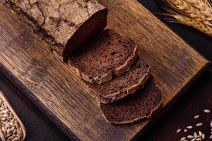 A loaf of brown bread with grains of cereals on a wooden cutting board photo