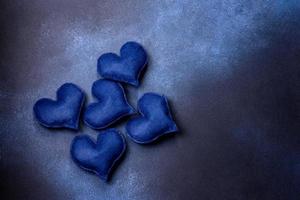 Beautiful felt hearts of blue color on a dark blue concrete background photo