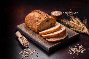 A loaf of brown bread with grains of cereals on a wooden cutting board photo