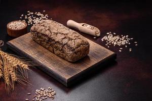 A loaf of brown bread with grains of cereals on a wooden cutting board photo