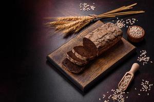 A loaf of brown bread with grains of cereals on a wooden cutting board photo