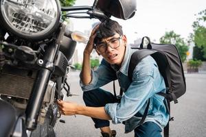 joven asiático reparando moto foto