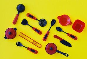 Creative composition of set of children's plastic tableware in red on a yellow background, top view. photo