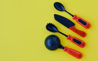 Creative composition of set of children's plastic tableware in red on a yellow background, top view. photo