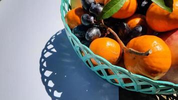 Close up of grapes and oranges in green basket on white background 02 photo