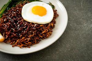 fideos instantáneos secos coreanos con salsa negra picante con huevo frito y kimchi foto