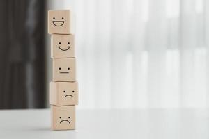 Mental health, Customer service rating experience and feedback emotion and satisfaction survey concept. Wood cube with smile, normal and sad face. Negative, neutral and positive facial expressions. photo