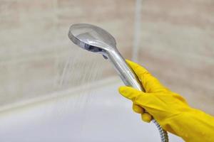 Female hand holds shower head with pouring water, copy space photo