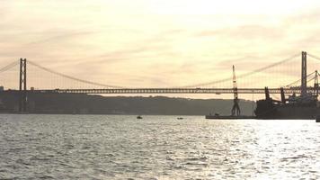 vista para a ponte 25 de abril o rio tejo com o trânsito rodoviário ao pôr-do-sol. pôr do sol no rio tejo ao final do dia video