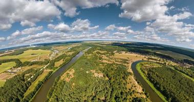 Curvature of space of little planet transformation. Abstract torsion and spinning of full panorama landscape over river and forest in sun day with clouds. video